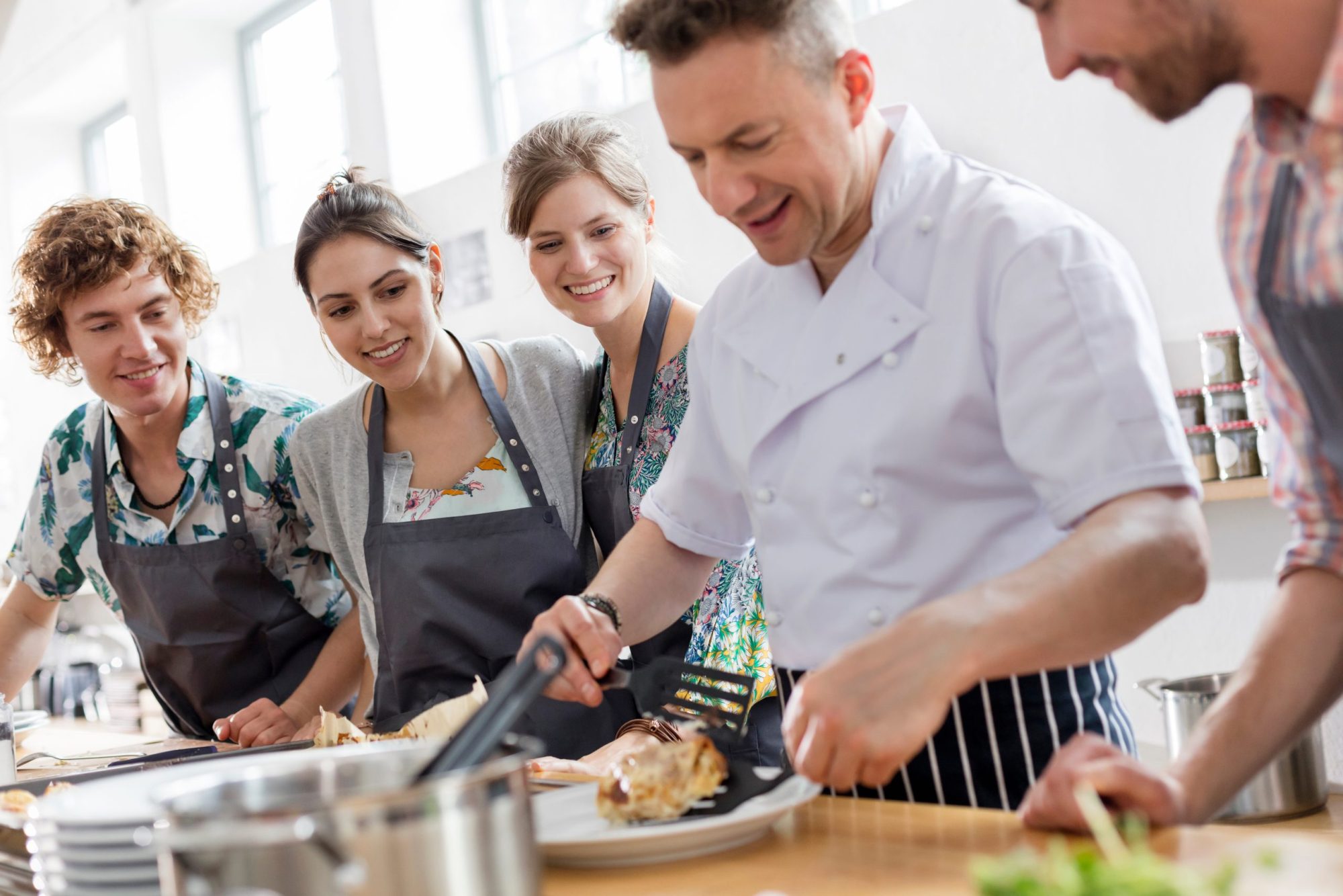 Students watching chef teacher in cooking kitchen